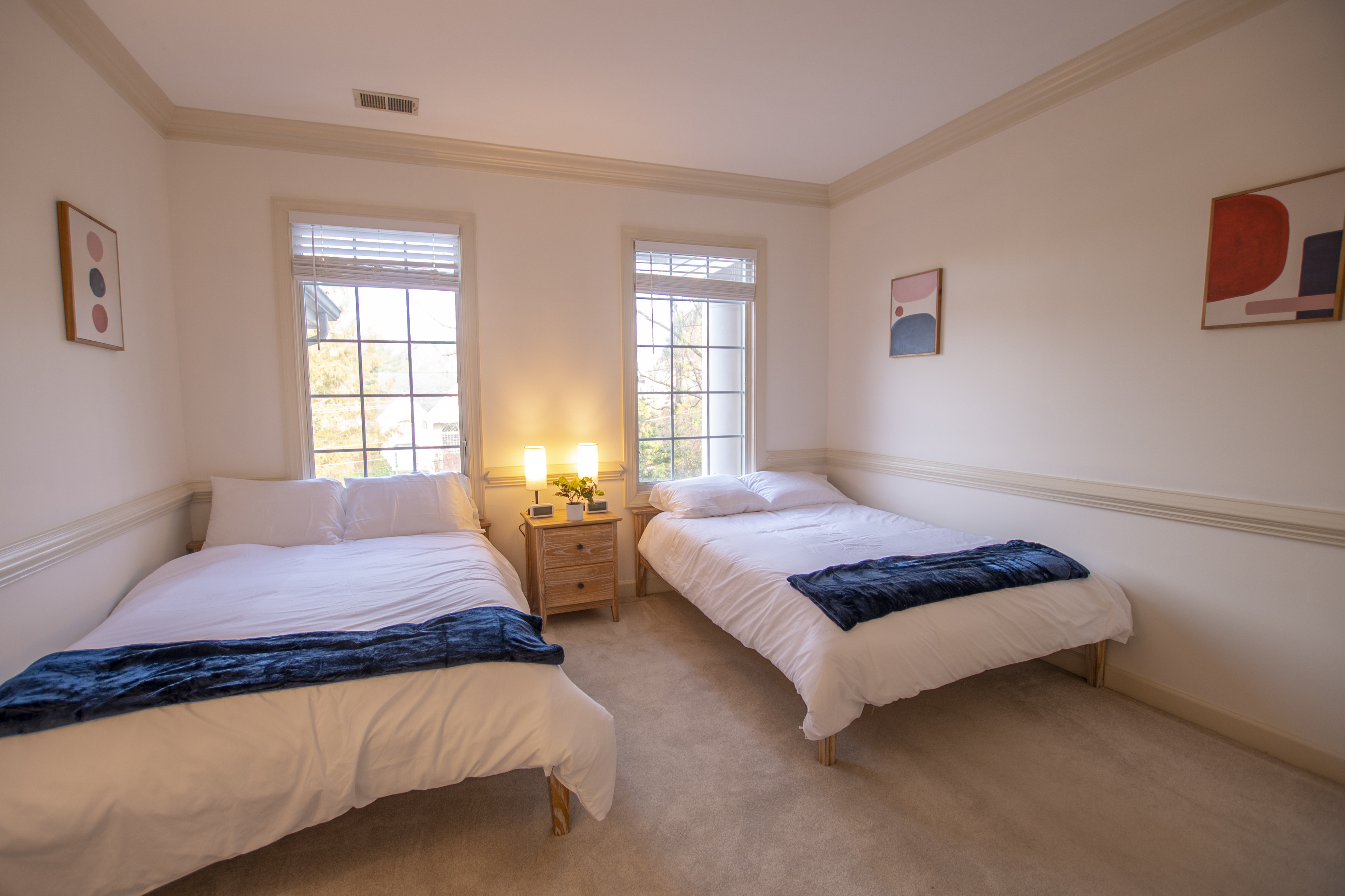 Two beds with nightstand and window light.