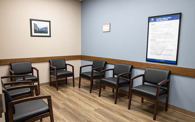 Waiting area with black chairs arranged along blue walls