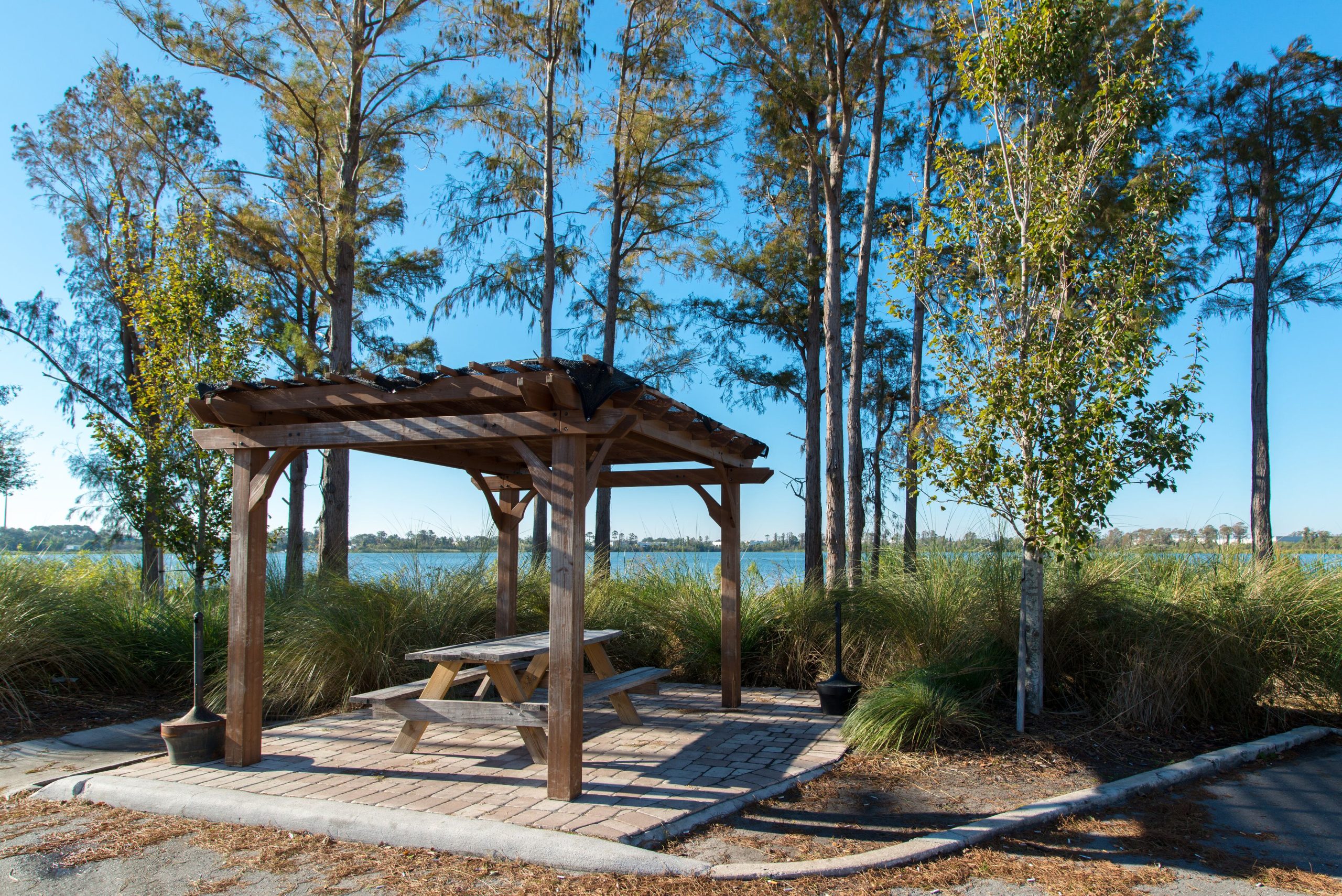 A serene outdoor seating area with a pergola overlooking a lake.