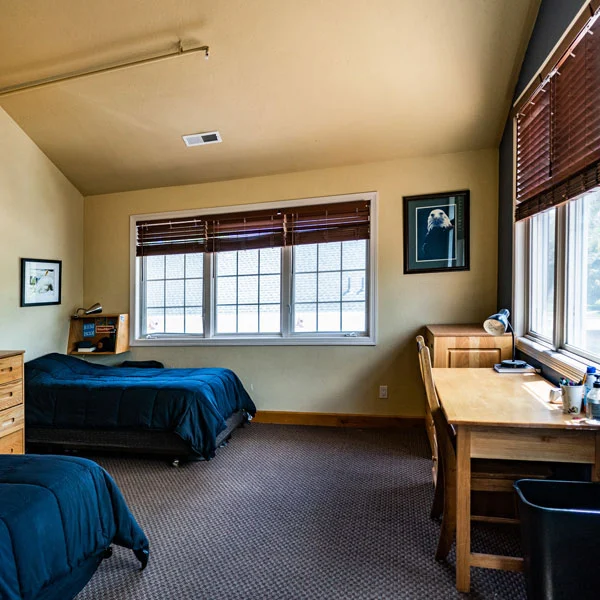 Shared bedroom with two beds and desks at Jaywalker Lodge