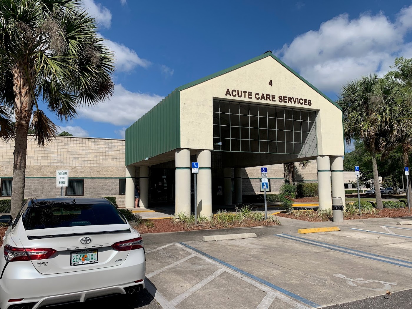 Acute care facility entrance with parking and palm trees