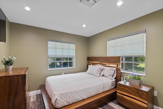 Bedroom with wood bed, nightstand, and two windows