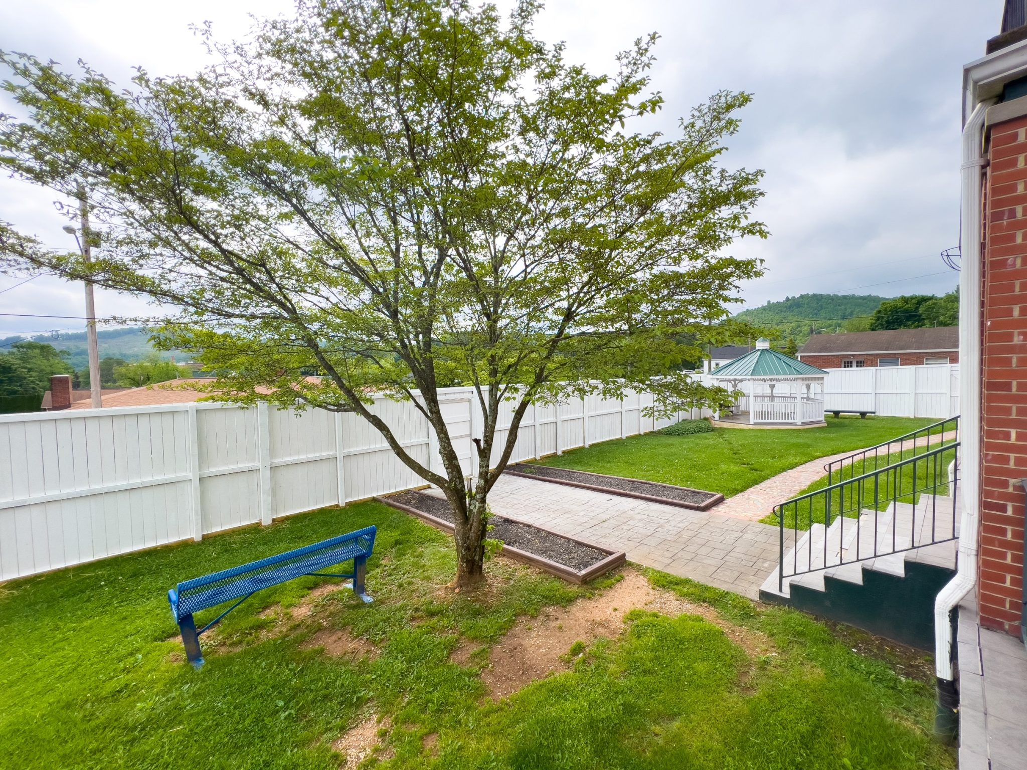 Fenced courtyard with shade tree, bench, and gazebo