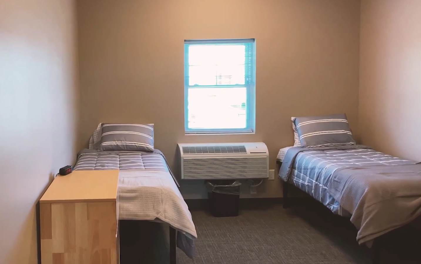 Shared bedroom with two beds, window, and air conditioning unit