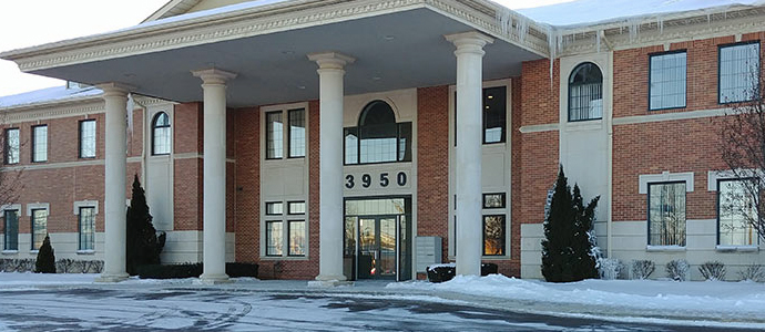Two-story brick building with tall white columns and glass entrance