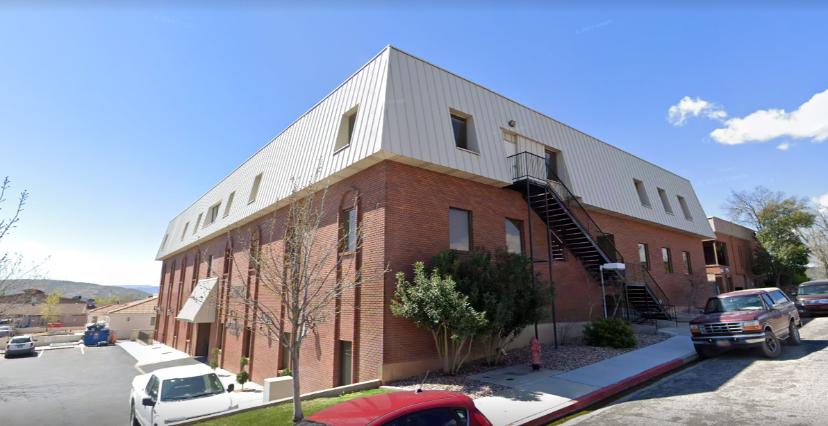 Three-story brick building with a white upper level and an exterior staircase.