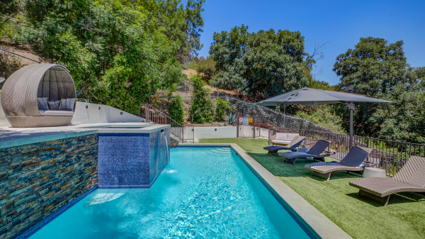Pool with lounge chairs, umbrella seating, and hillside view
