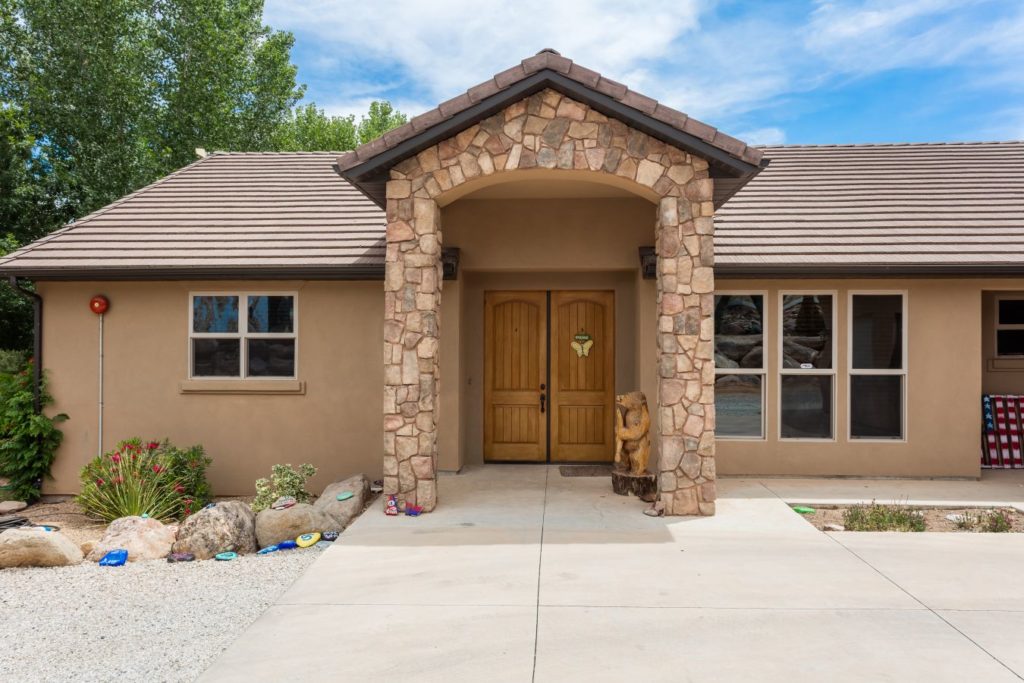 Front entrance with stone pillars and wooden double doors.