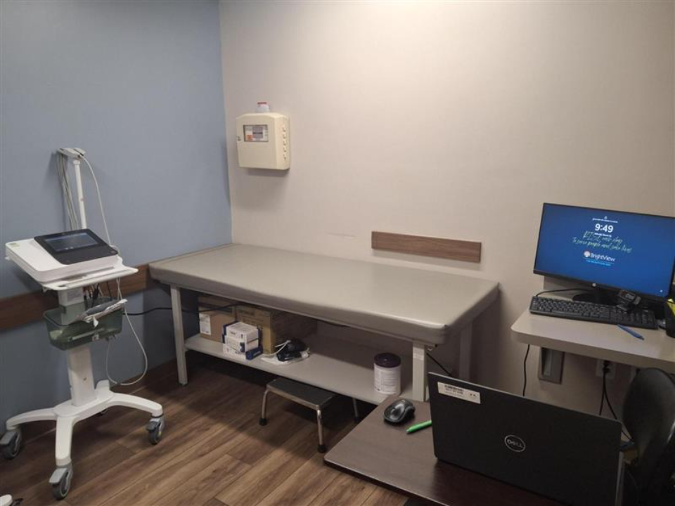 BrightView Health Batavia exam room with exam table, medical equipment, computer workstation, and wood-look flooring