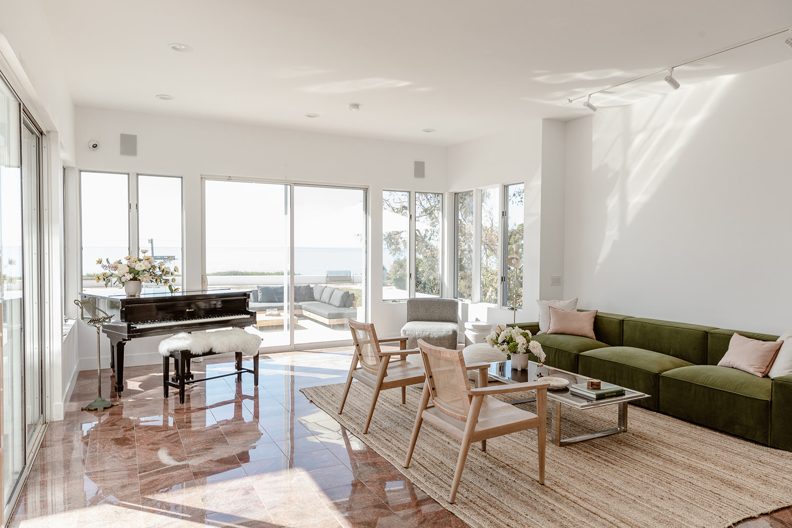 Spacious living room with ocean views, green sofa, and grand piano.