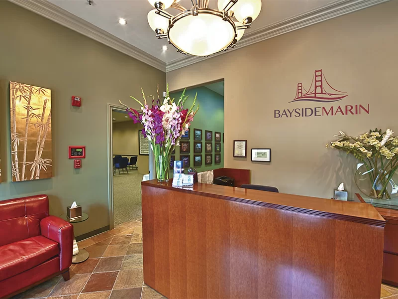 Front desk reception with floral arrangement and Bayside Marin signage