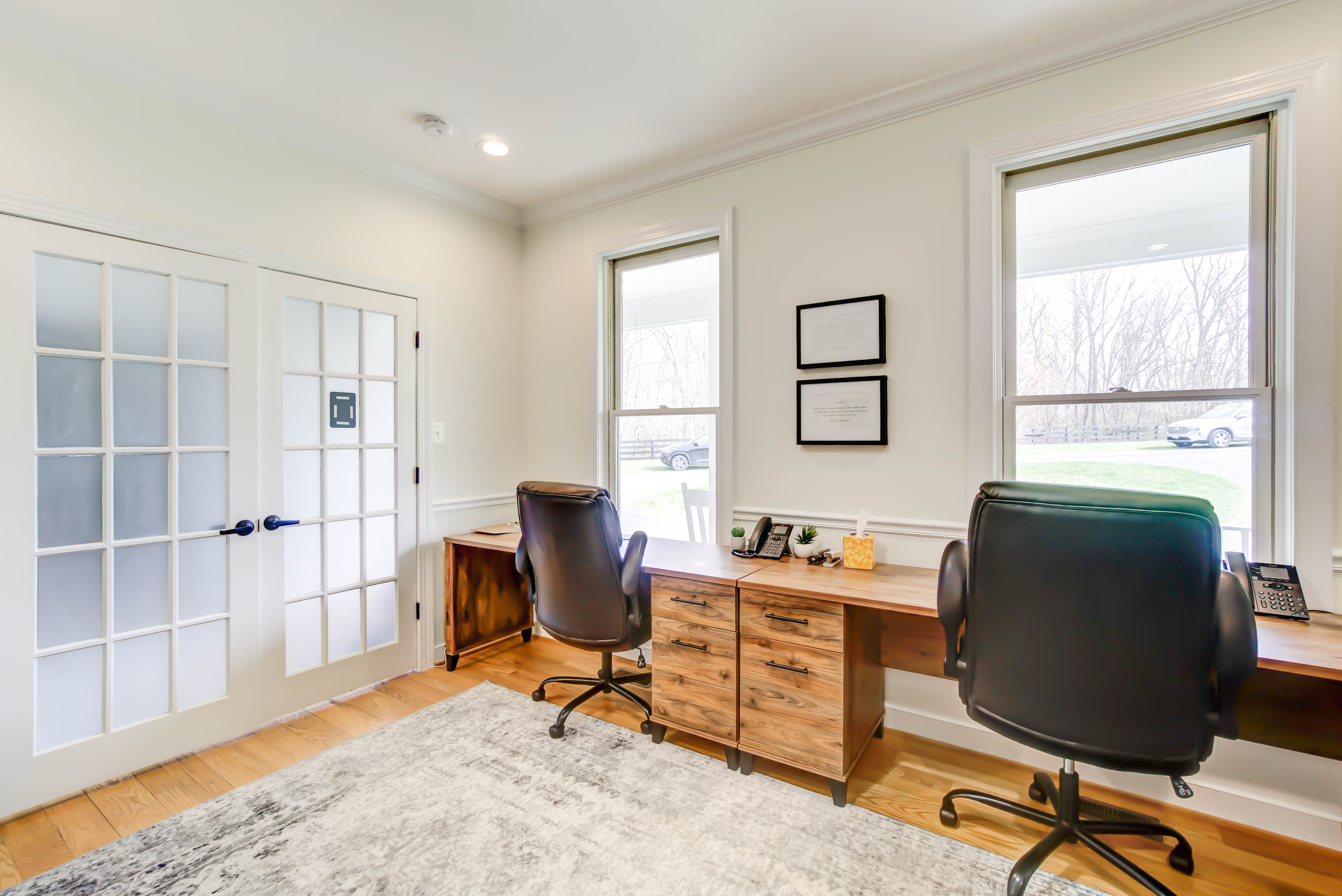 Two desks with chairs by windows in a quiet office room