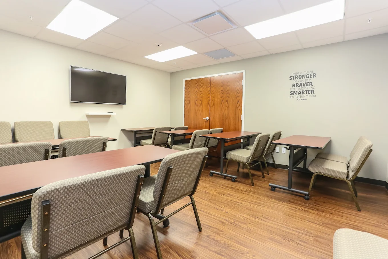 Meeting room with tables, chairs, and a wall-mounted TV