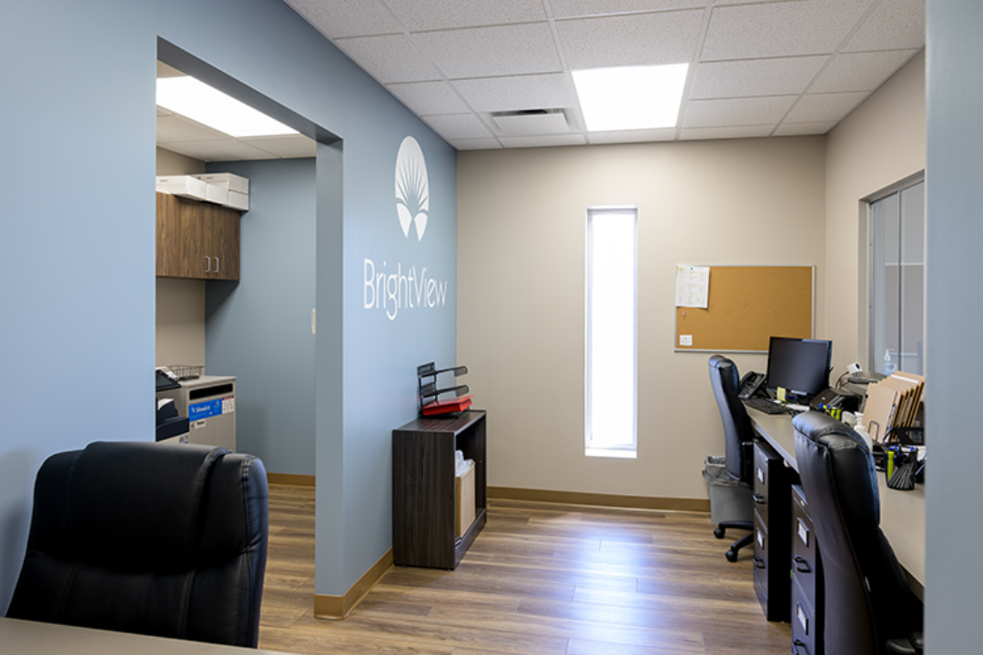 Staff workstation with desks, computers, storage cabinets, and BrightView logo on blue wall