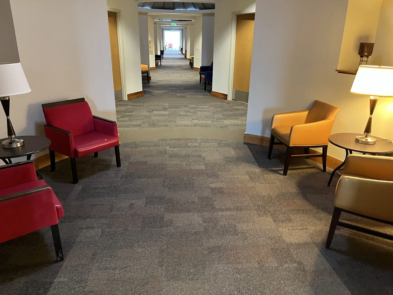 Carpeted hallway with lounge chairs and side tables