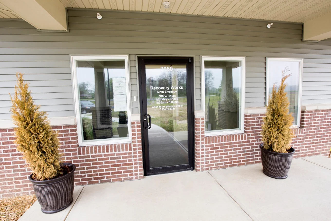 Glass entrance doors with potted plants on either side