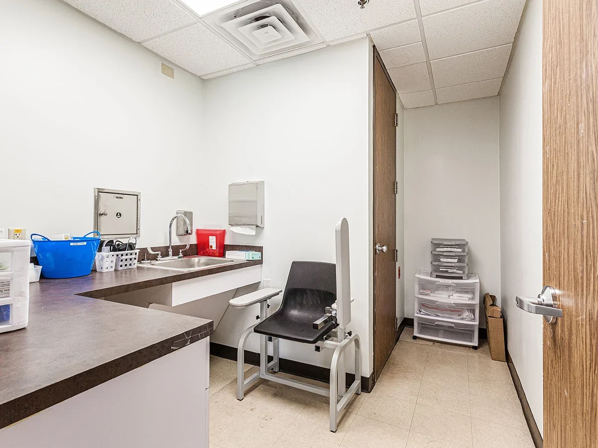 Clinical room with sink, chair, medical supplies, and storage containers