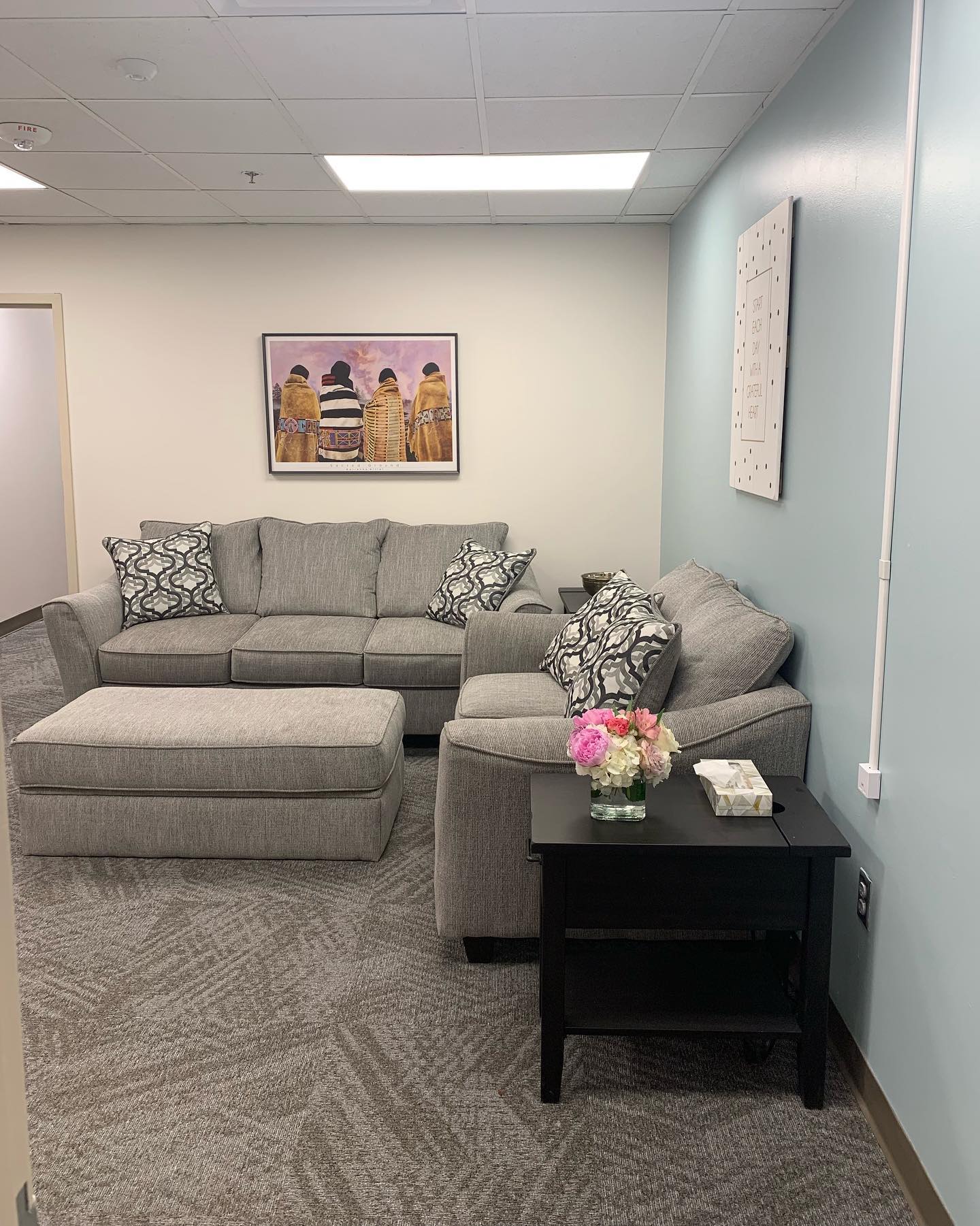 Cozy lounge with gray sofa, ottoman, and wall art