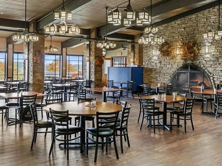 Dining area with stone fireplace, tables, and large windows