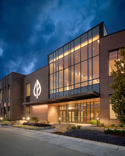 Glass-front rehab facility entrance lit up at dusk