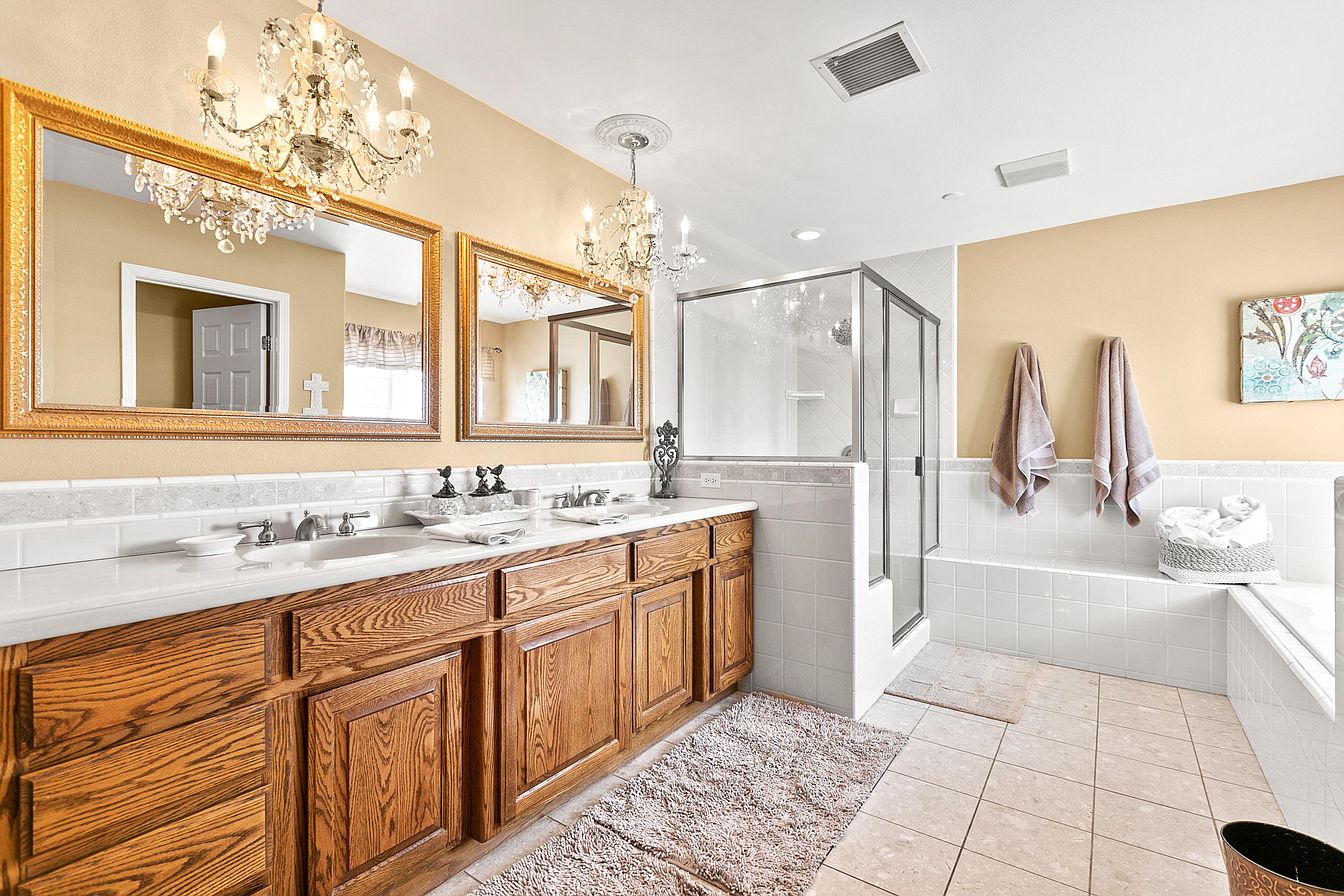 Bathroom with chandelier, dual sinks, and walk-in shower