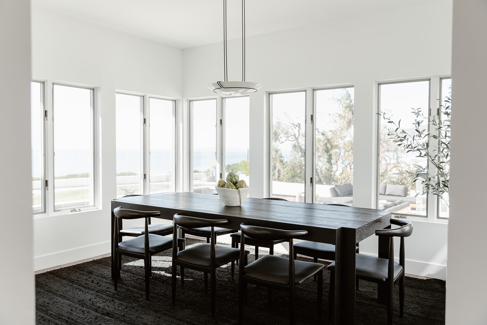 Minimalist dining room with large windows and ocean views.