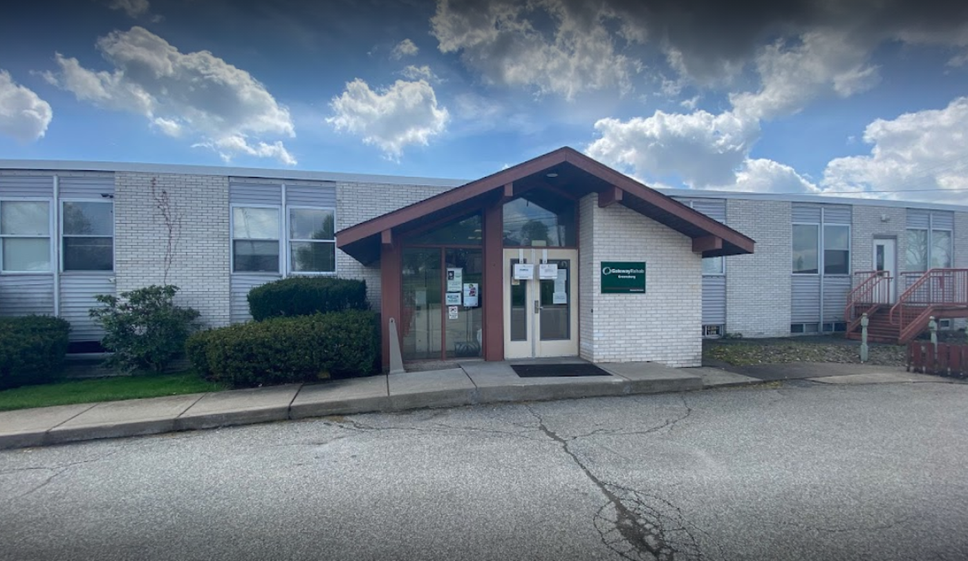 Single-story brick rehab building with glass entry and overhang