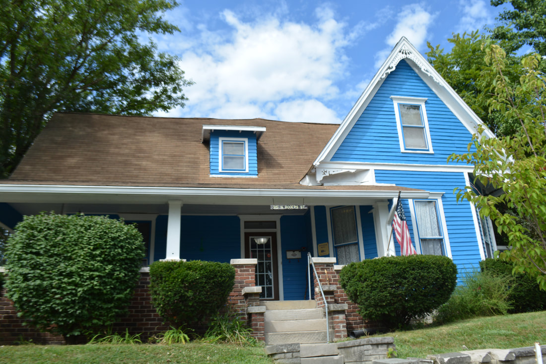 Blue rehab house with porch, steps, and trimmed bushes