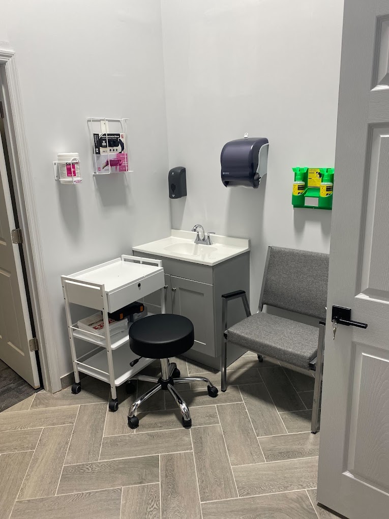 A clean medical exam room with seating and a sink.