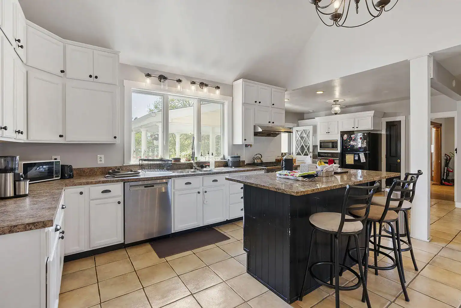 Spacious community kitchen with island seating, granite countertops, and modern appliances at Southern Maine Recovery