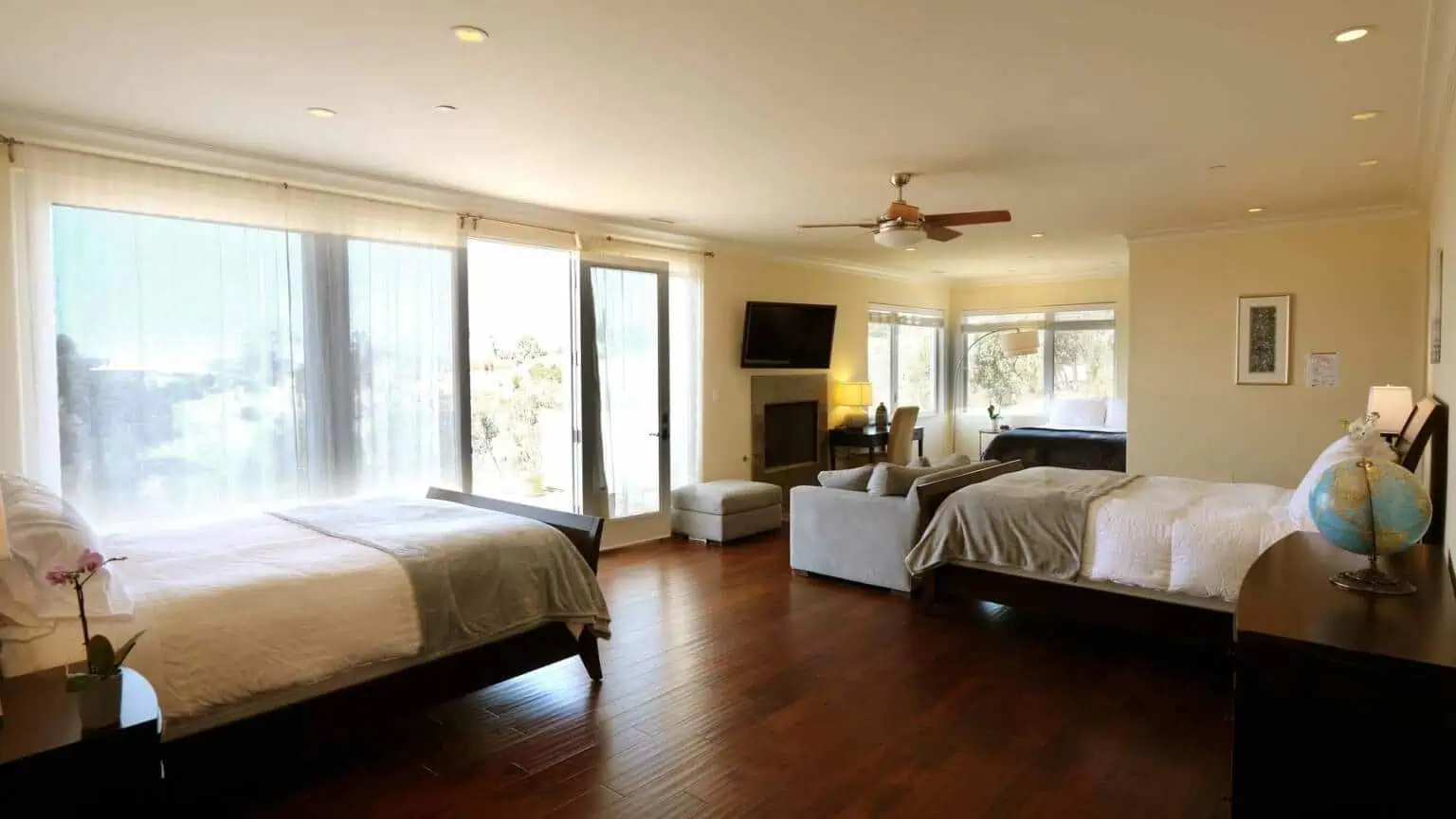 Shared bedroom with two beds, wood floors, and large windows