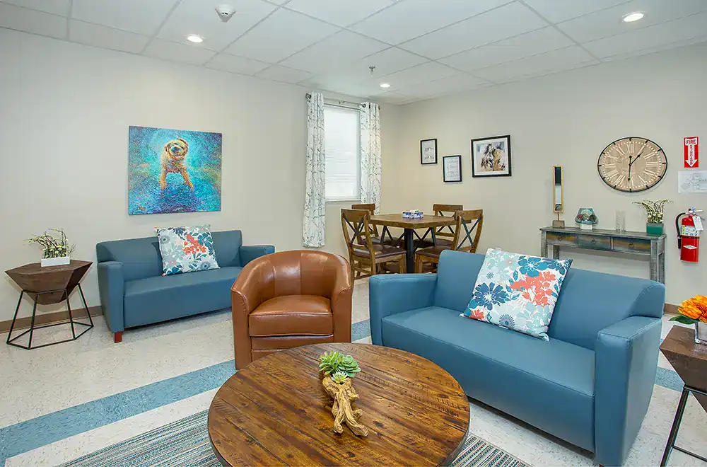 Blue sofas, leather chair, and game table in common room