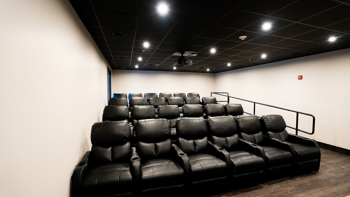 Private theater with black reclining seats and projector.