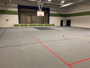 Gymnasium with basketball hoop and stage area