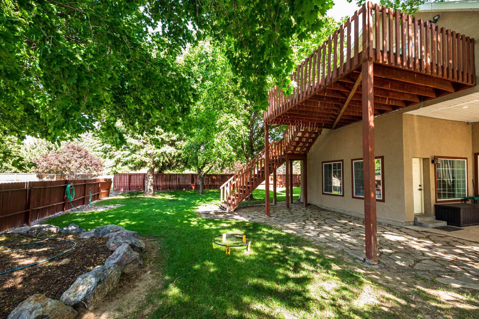 Backyard with wooden deck, stairs, and green lawn