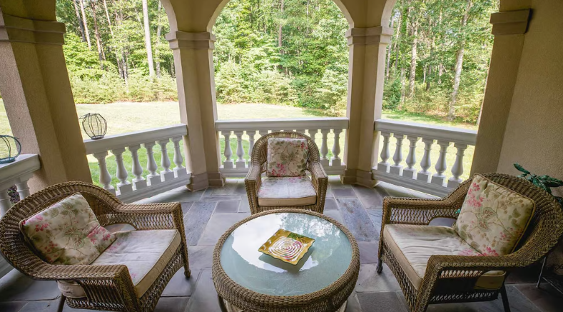 Covered patio with wicker chairs and forest view