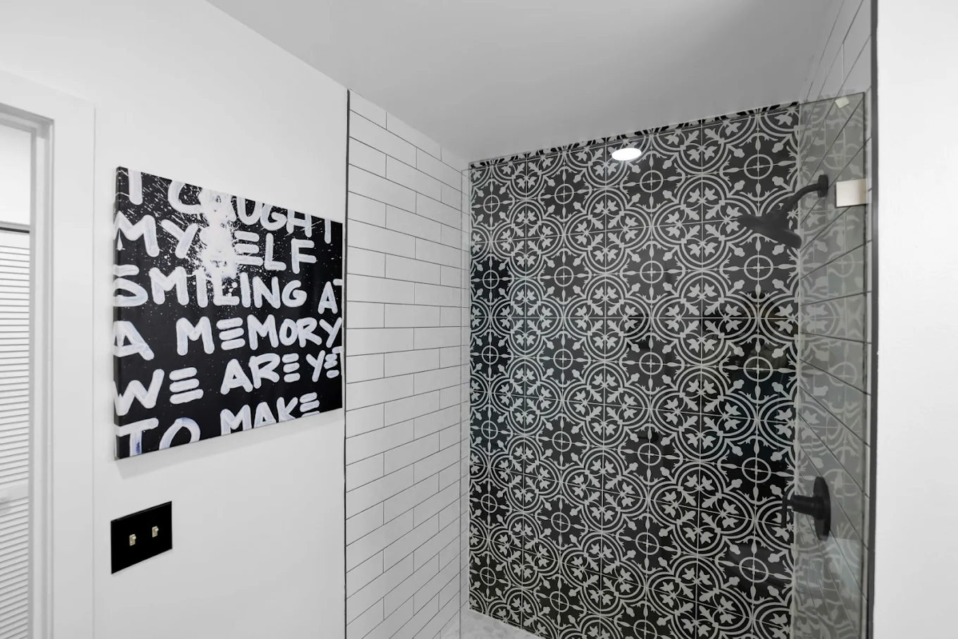 Glass-enclosed walk-in shower with decorative tile wall