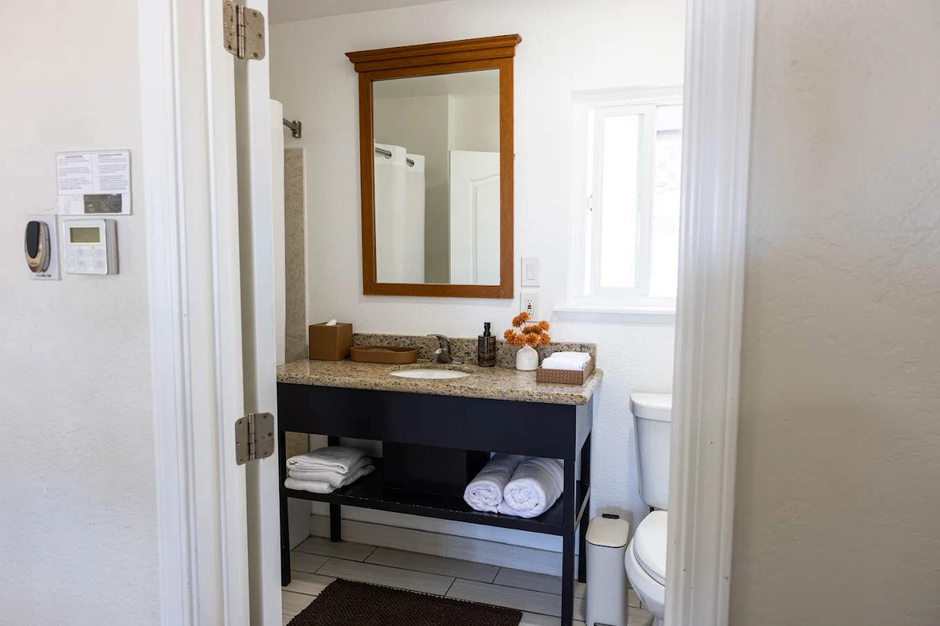 Bathroom vanity with sink, wooden mirror, and folded towels