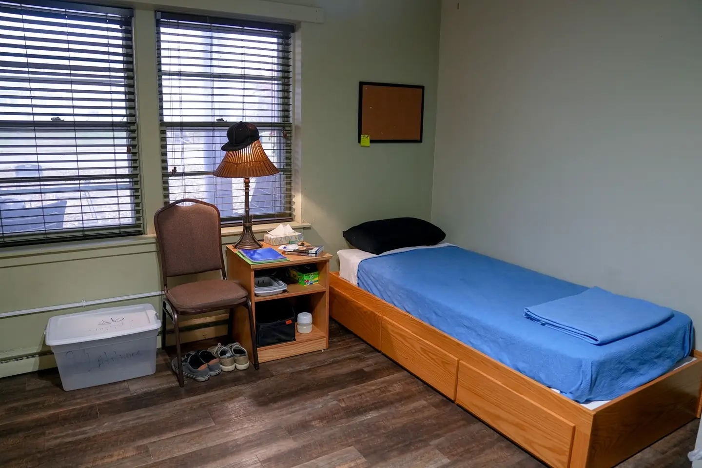 Single bed with blue blanket in a modest bedroom