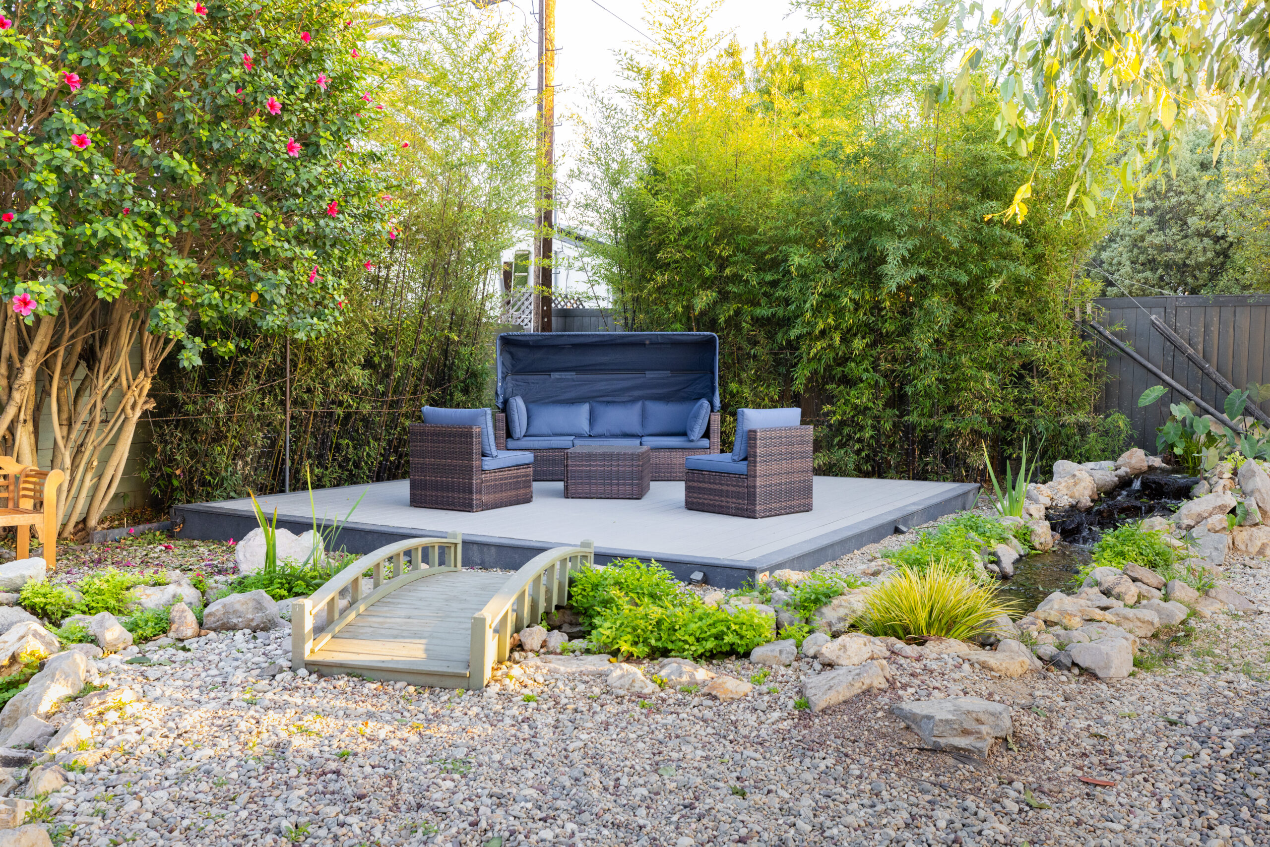Garden lounge deck with chairs and sofa near a creek