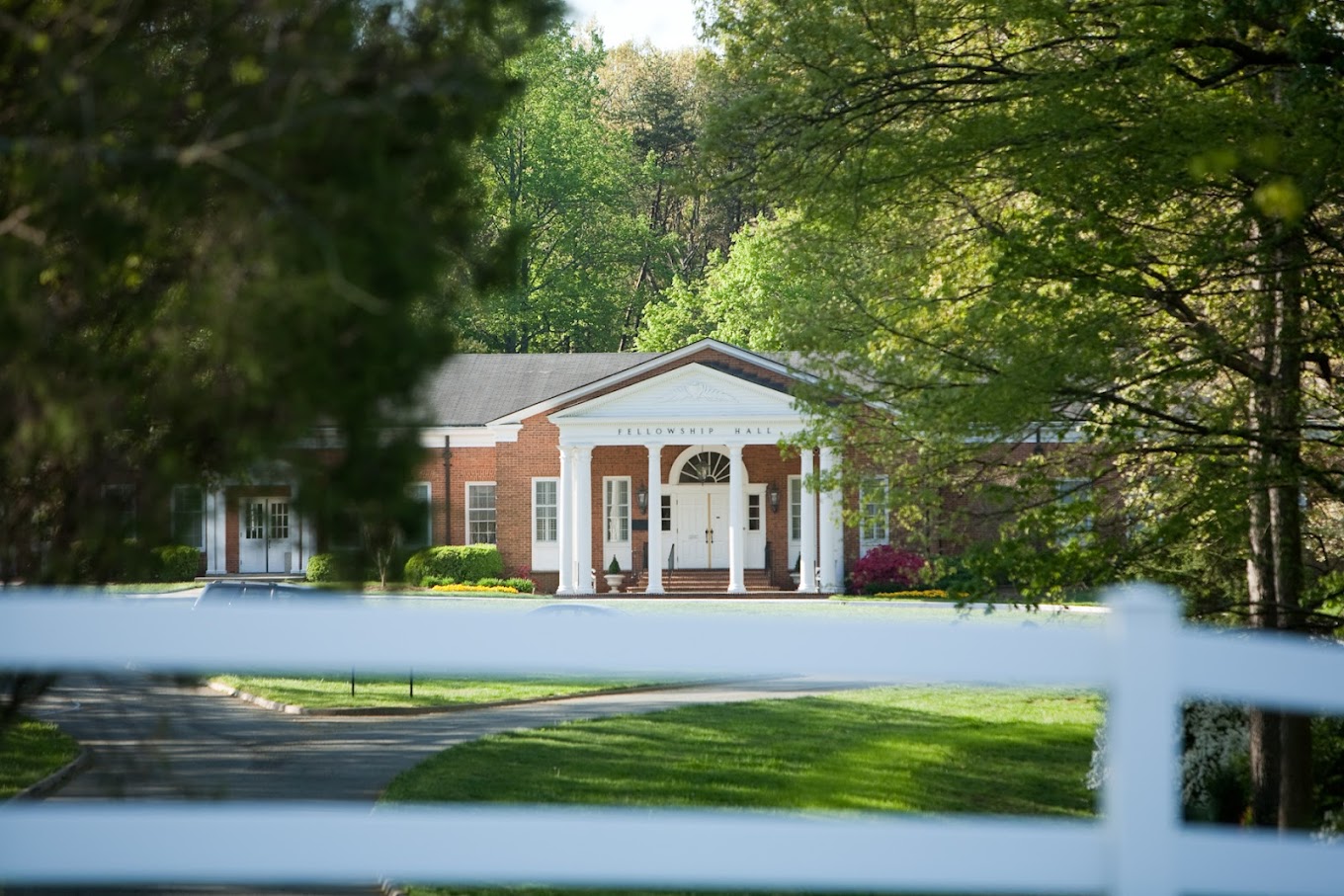 Street view of Fellowship Hall's building behind a lawn and walkway.