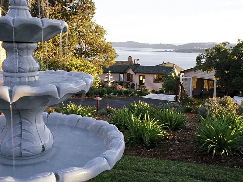 Decorative fountain in foreground with scenic water and hillside view