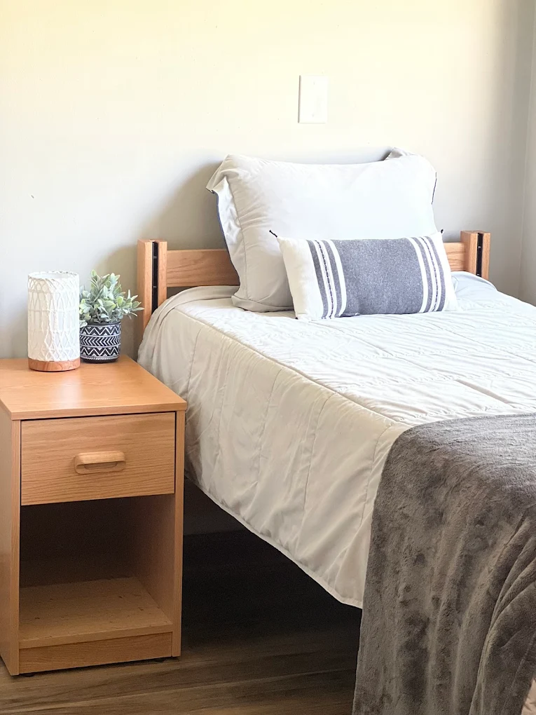 Single bed with white bedding and a wooden bedside table