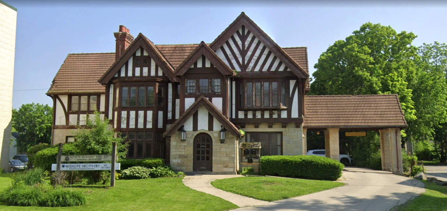 Tudor-style building with front lawn and sign