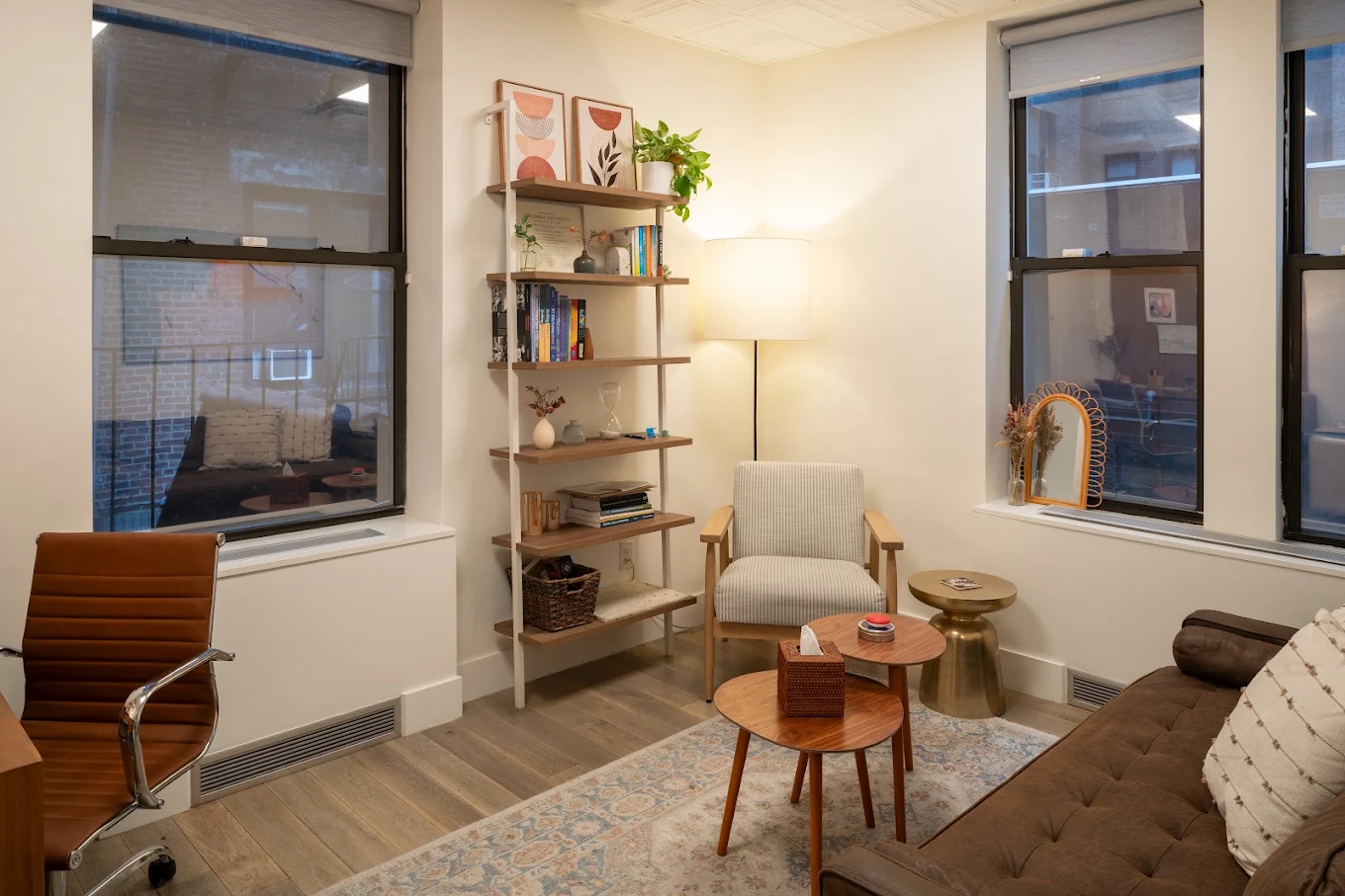 Therapy room with sofa, chairs, shelving, and large windows