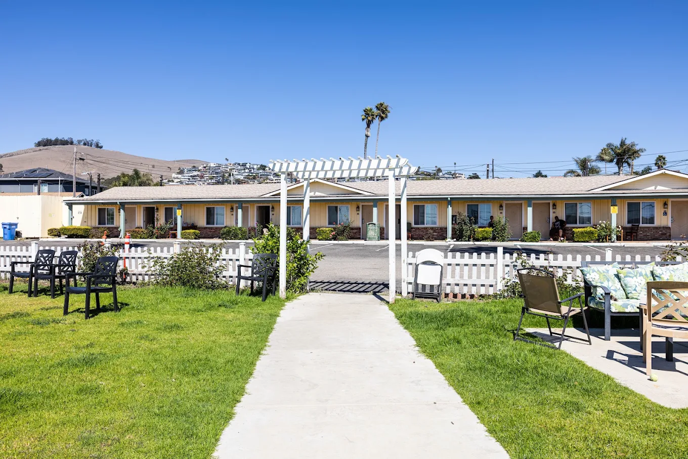 Green lawn with walkway leading to a white pergola and building