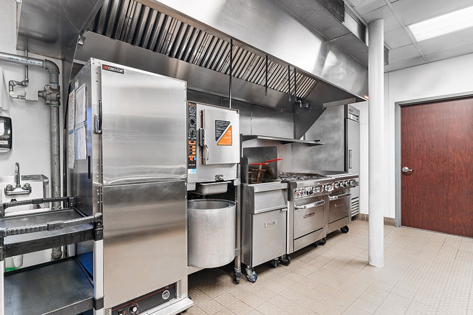 Industrial-style kitchen with ovens, stovetops, and vent hood