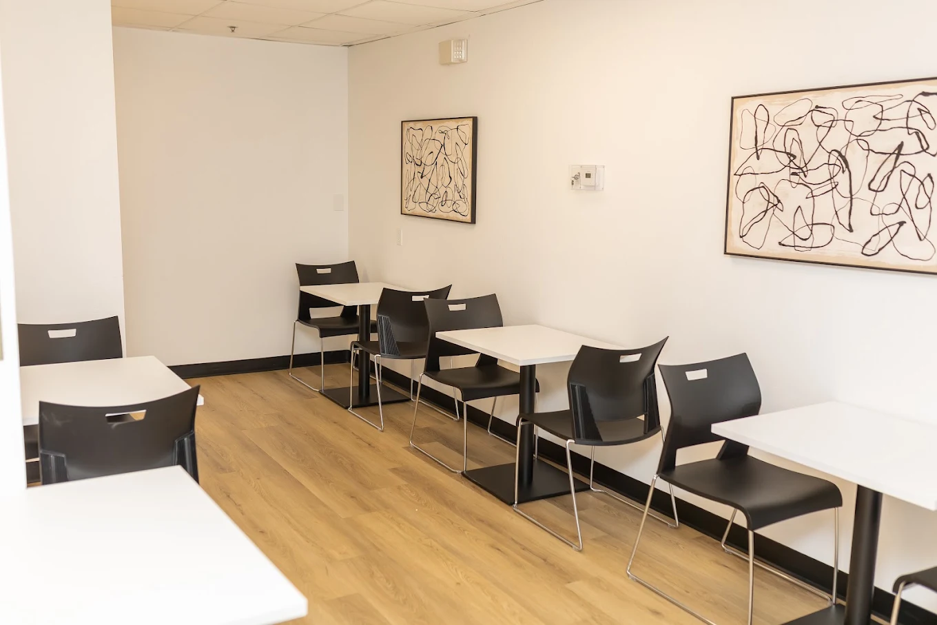 Dining area with tables and chairs along white walls