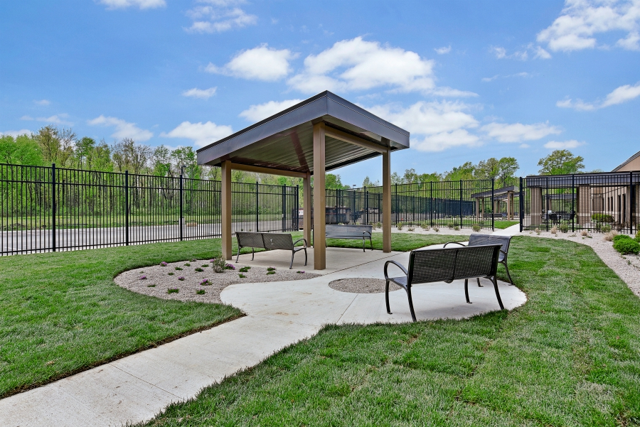 Covered outdoor sitting area with benches and fenced lawn