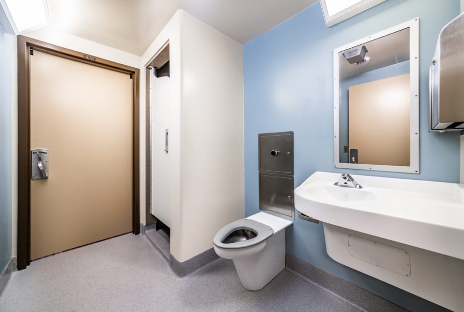 Clean single-stall restroom with sink and safety fixtures